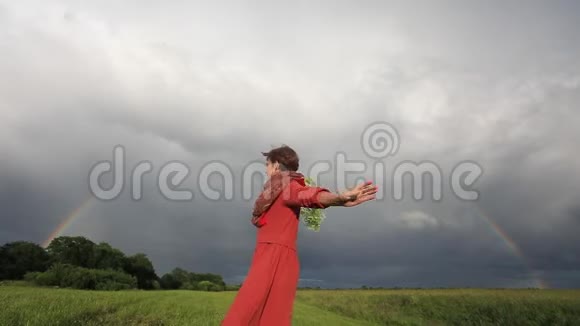 一位身着民族服装的妇女在暴风雨天的背景下拿着花圈在纺纱慢动作视频的预览图