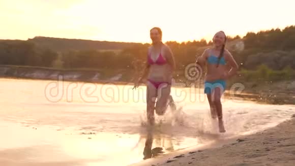 女孩们在沙滩上奔跑在海滩上溅起水滴笑着快乐自由的青少年视频的预览图