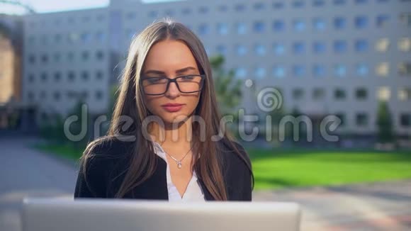 在户外使用笔记本电脑的年轻有魅力女商人的特写镜头坐在楼梯上的漂亮女学生视频的预览图