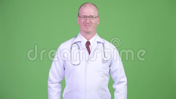 快乐成熟的秃头医生双臂交叉在绿色背景下视频的预览图