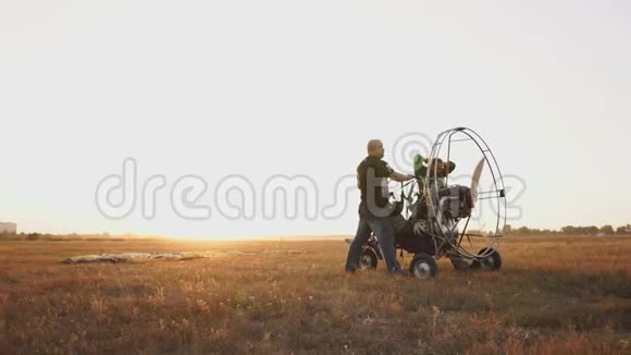 汽车滑翔伞在日落时分用一个木制螺旋桨站在田野里两名飞行员对发动机进行了一次试车视频的预览图