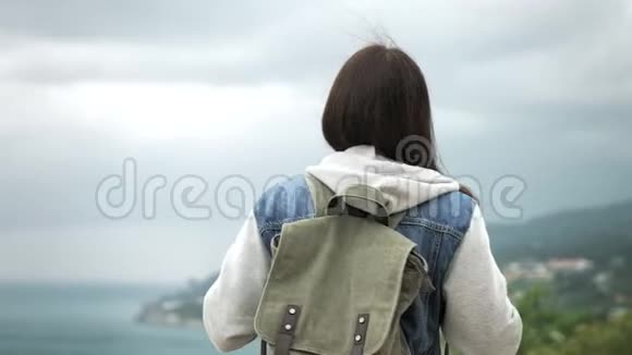 后景背包客女站在山顶欣赏海景视频的预览图