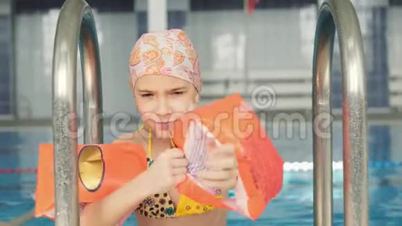游泳池里的一个小女孩穿着充气臂游泳视频的预览图