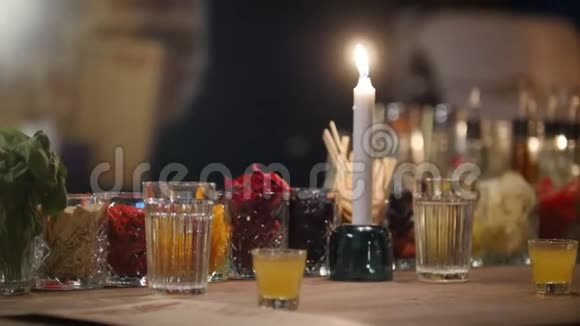 戴着眼镜的彩色鸡尾酒和酒吧柜台上的蜡烛视频的预览图