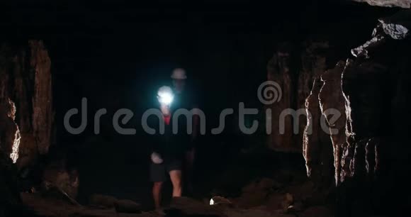 两个年轻人拿着手电筒在黑暗的洞穴里散步视频的预览图