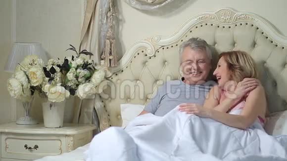 兴奋的老夫妇在床上一起笑视频的预览图