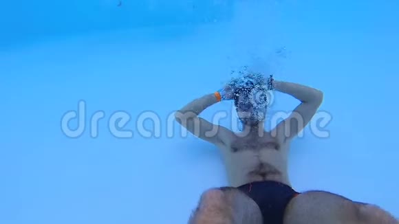 他躺在游泳池底部的背面对着镜头微笑积极休息视频的预览图