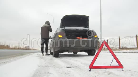 冬季驾驶汽车故障在下雪的乡间小路上遇到了汽车故障一个年轻人叫救援人员视频的预览图