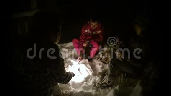 一群人晚上在雪地上燃烧篝火用棍子炸香肠视频的预览图