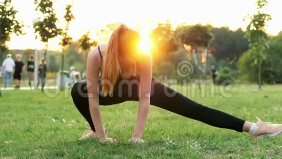 美丽的运动女孩做健身和伸展运动日落时在公园训练视频的预览图