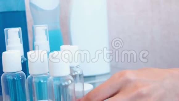 女人手把蓝色的洗发水倒进一小瓶大的旅行的罐子瓶子特写视频的预览图