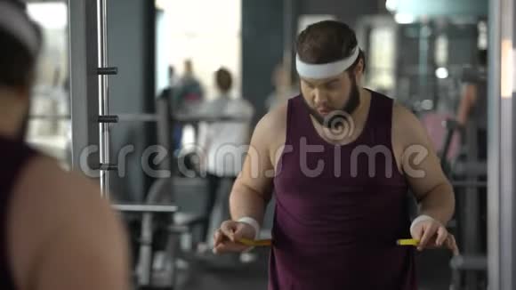 愤怒的胖男人因为测量腰部成绩而失望运动视频的预览图