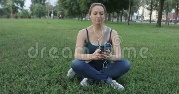 在公园里用手机听音乐的女人视频的预览图