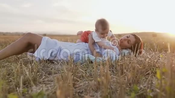 年轻的女人和她可爱的6个月的男孩在野外玩一位年轻的母亲抱着一个小儿子视频的预览图