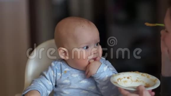 第一个喂养宝宝孩子坐在高椅上妈妈给他一勺水果泥孩子没有视频的预览图