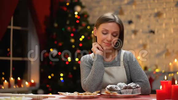 年轻女士端着巧克力松饼坐在桌子上准备圣诞礼物视频的预览图