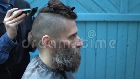男士在户外理发店理发时用电动剃须刀剪头视频的预览图