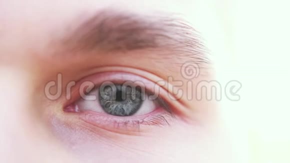 闭上一只灰色的雄性眼睛一个人看着摄像机的灰色眼睛的细节慢动作视频的预览图