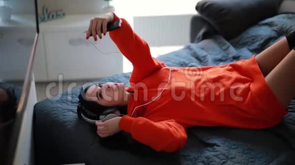 年轻女孩通过智能手机聊天在线视频聊天躺在家里的床上视频的预览图