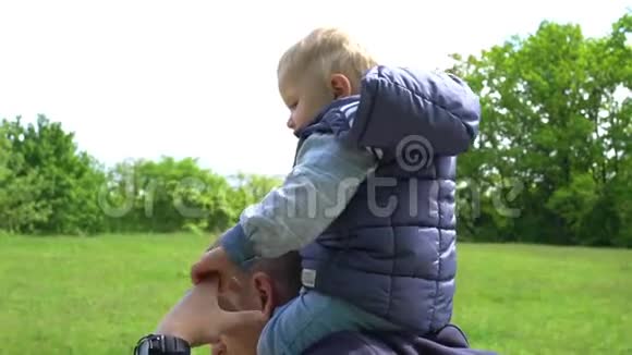 小男孩坐在公园里他父亲脖子上父亲天视频的预览图