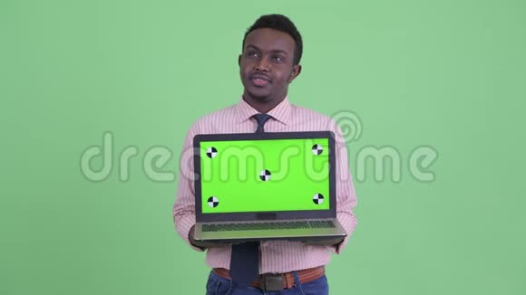 快乐的年轻非洲商人一边思考一边展示笔记本电脑视频的预览图