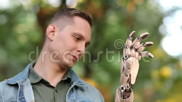 年轻人在公园里看着他的机器人手美丽逼真的三维动画4K视频的预览图
