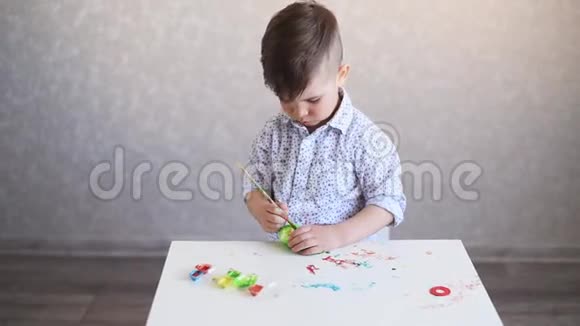 小孩子在桌子上画一个白色背景的复活节彩蛋视频的预览图