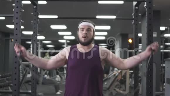 胖乎乎的男人在健身房里跳绳在锻炼前热身慢动作视频的预览图