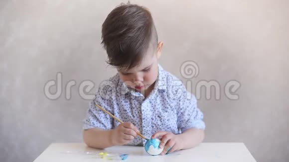 一个小孩在桌子上画一个白色背景的复活节彩蛋视频的预览图