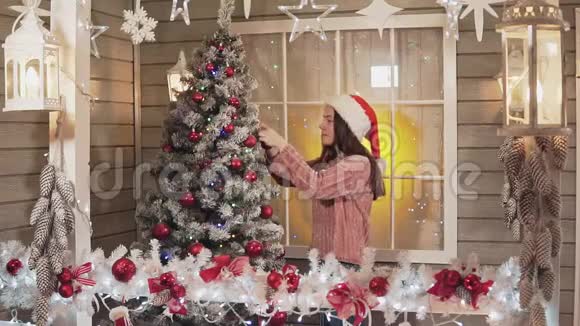 小女孩用红球装饰圣诞树在斯洛莫的门廊视频的预览图