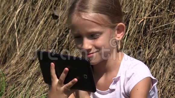 乡村小女孩在4K自然放松的乡村女孩户外玩平板电脑视频的预览图