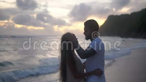 情侣们在海滩日落时接吻在异国情调的地方度过浪漫的夜晚视频的预览图