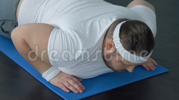 胖子摔倒在瑜伽垫上试图做木板运动缺乏能量视频的预览图