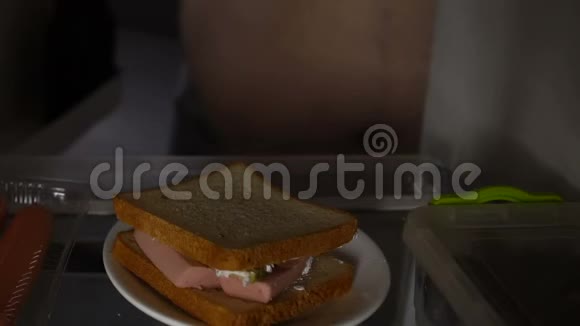 饥饿的单身汉把三明治冰箱关紧生活质量差消费主义视频的预览图