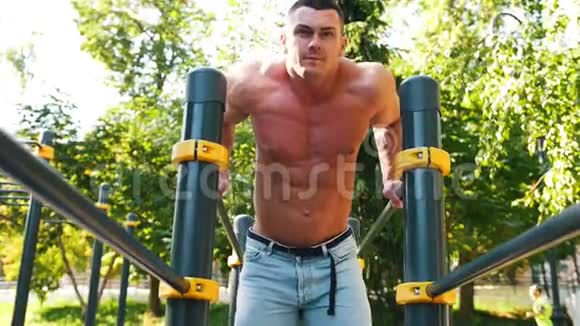 强壮的肌肉男在夏季公园锻炼横杠视频的预览图