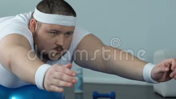肥胖男子放松健身球后家庭锻炼复杂力量和耐力视频的预览图