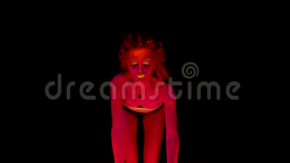 一个美丽的半裸的年轻女子跪在四个人身上她的身体在黑色的灯光下发光视频的预览图