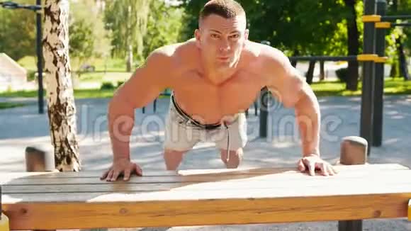 户外长凳上的肌肉运动员俯卧撑视频的预览图