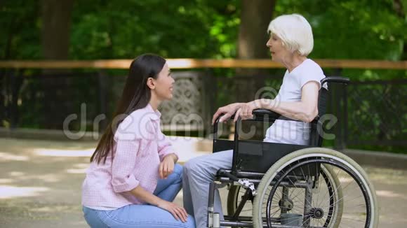 微笑志愿者与轮椅上的老妇人交谈残疾人支持视频的预览图