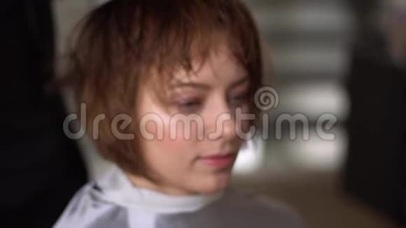 理发师用剪刀给美容院里的一个年轻女孩理发视频的预览图