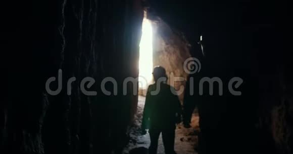 戴着头盔的年轻朋友探险者离开黑暗的洞穴视频的预览图