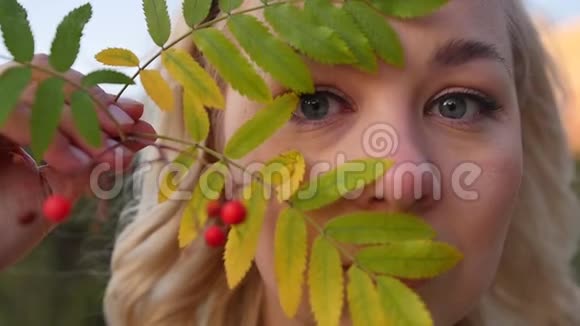 一个美丽的年轻金发女郎的肖像脸附近有一堆山灰秋天在一个城市公园里拍摄慢动作视频的预览图