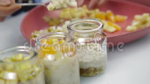 女人手把层层的水果放进透明的碗里烹饪美味的家做甜点视频的预览图