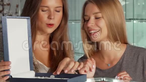 两个漂亮的女朋友在商店里检查一个盒子里的珠宝视频的预览图