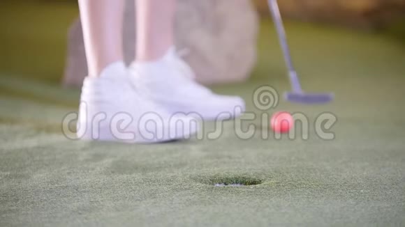 打迷你高尔夫一个穿着白色球鞋的人打高尔夫球时视频的预览图