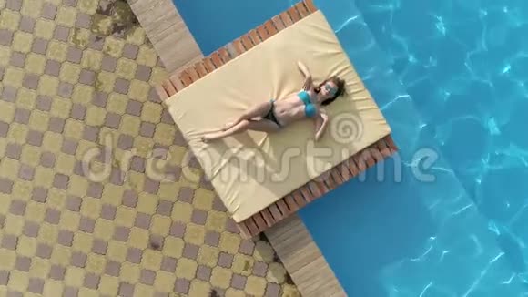 戴着眼镜和泳装的女孩的鸟瞰景色令人愉快夏天就在蓝水游泳池附近视频的预览图