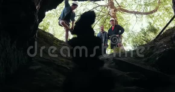 一群快乐的朋友探险者站在森林洞穴的入口处视频的预览图