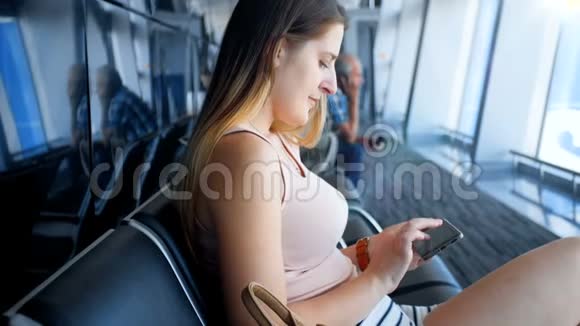 4k视频坐在国际机场候机楼的年轻美女手机打字视频的预览图