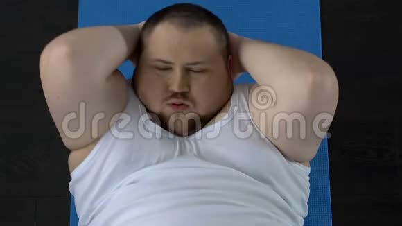 身材矮小的男人做仰卧起坐运动在地板上休息缺乏体育锻炼视频的预览图