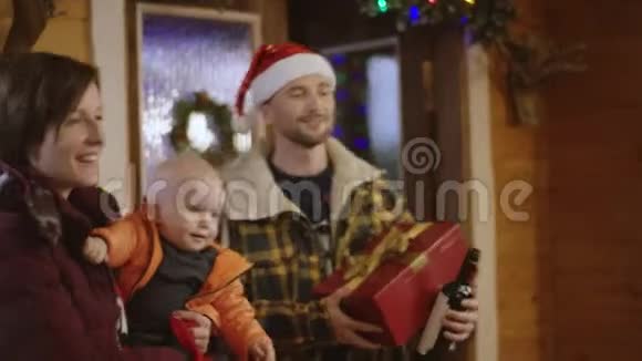一对带着小孩的家庭夫妇给他们的朋友送圣诞礼物和葡萄酒视频的预览图